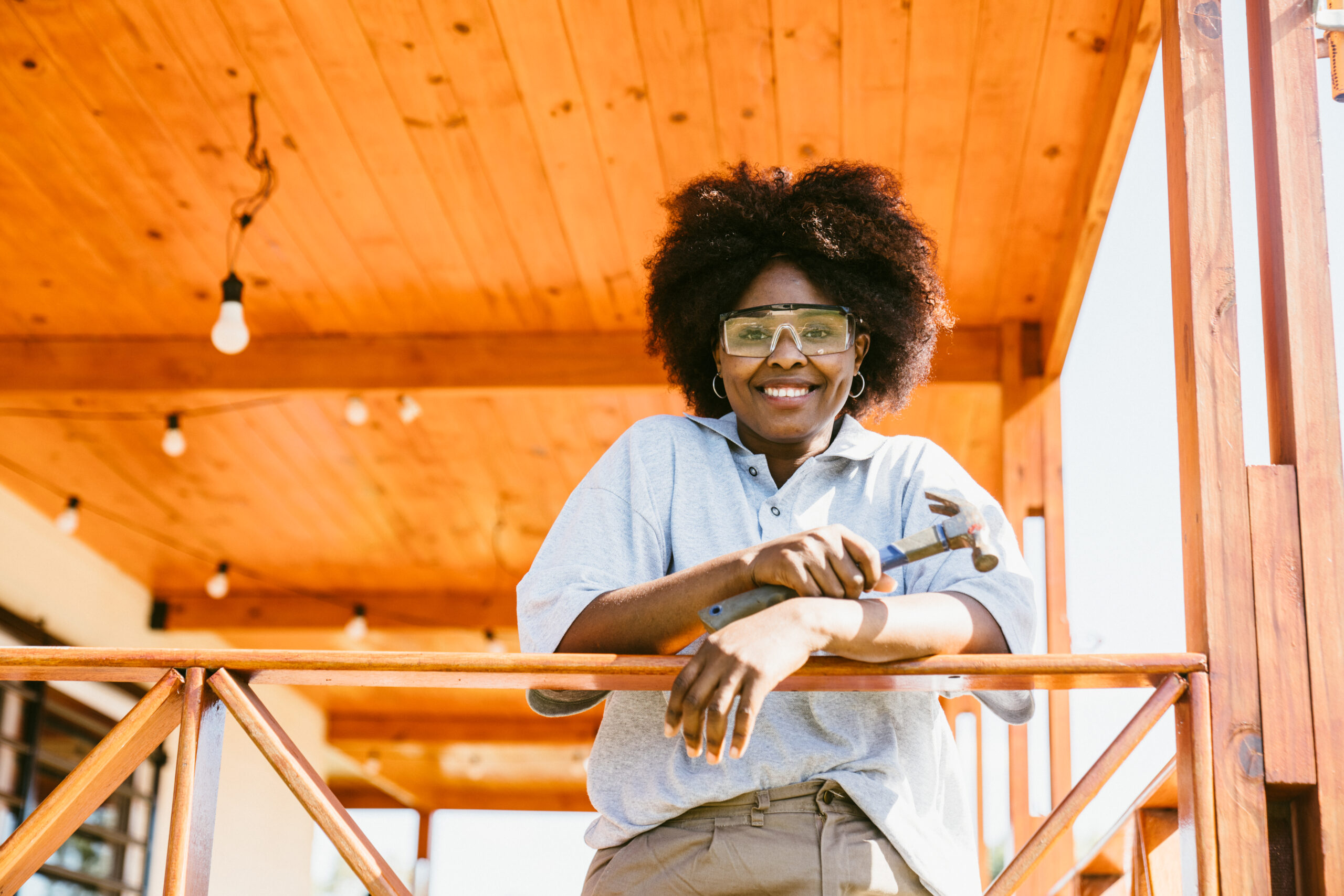 African American Woman standing on porch holding a hammer.